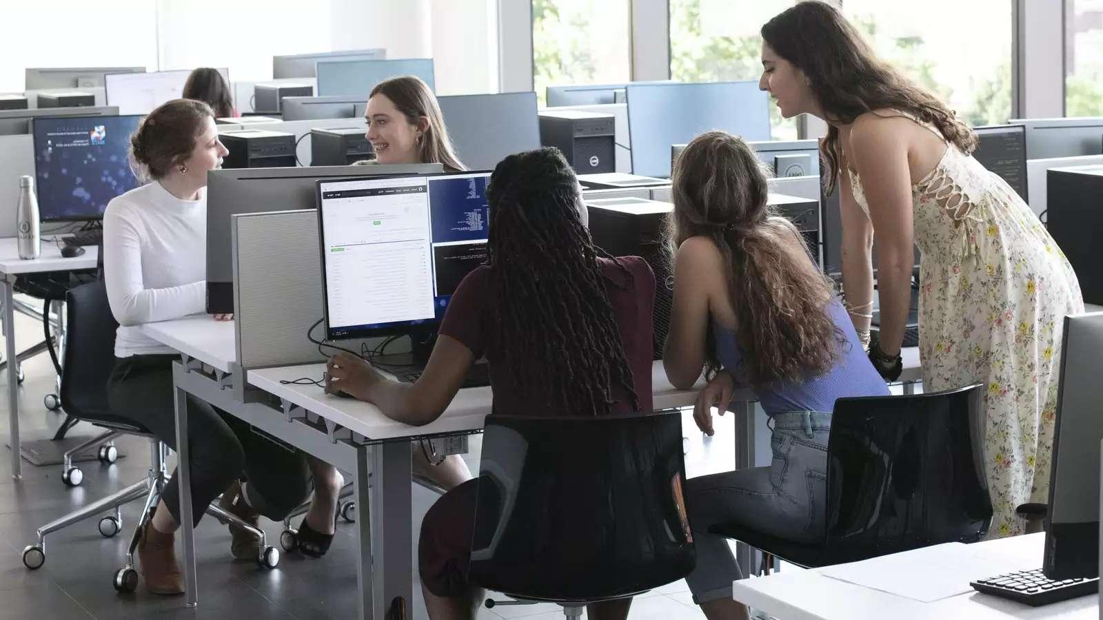 Students in the CSC classroom look at a computer screen together.